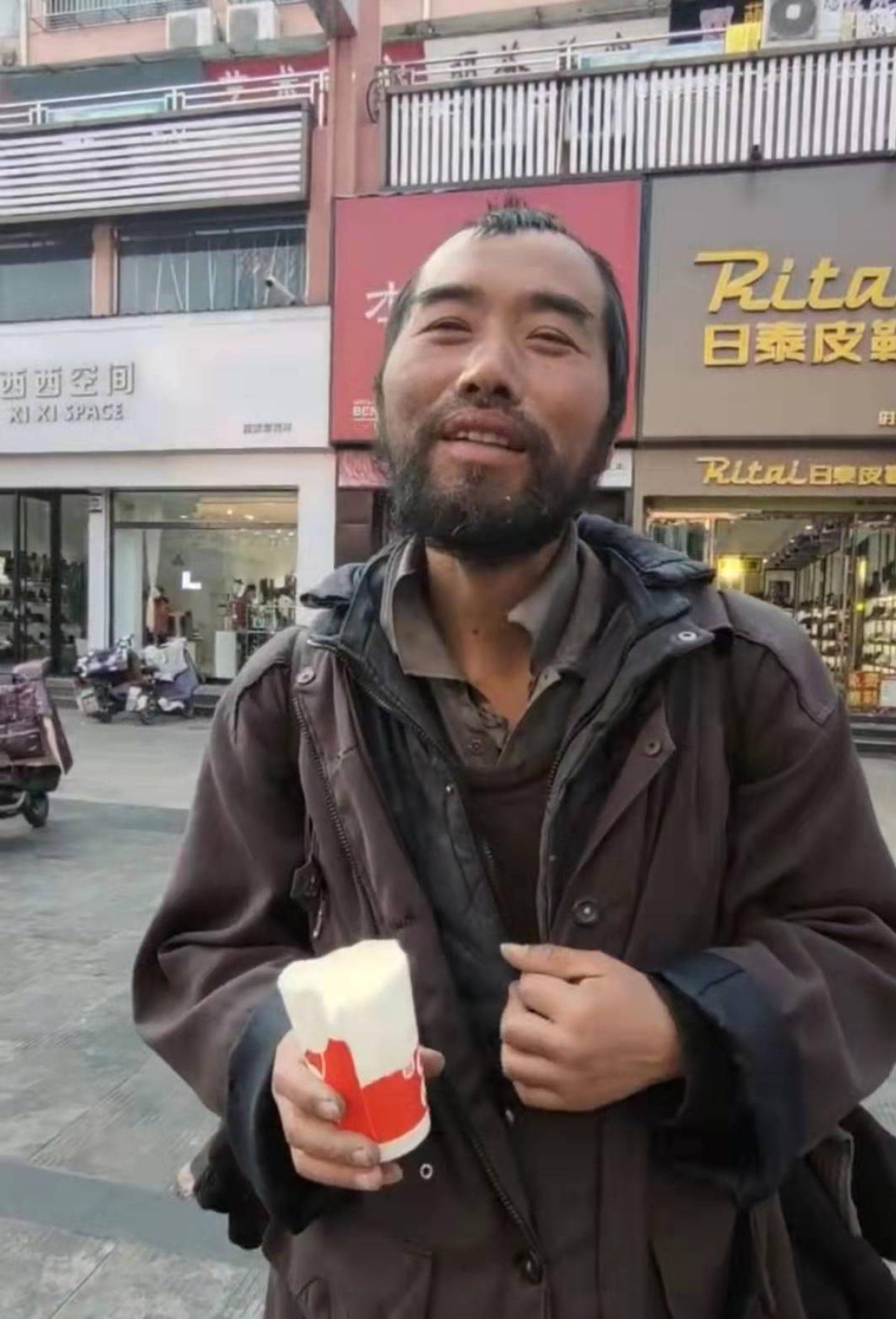 视频中,一位流浪者留着络腮胡在山东滕州某街道转悠,外表邋遢但面对
